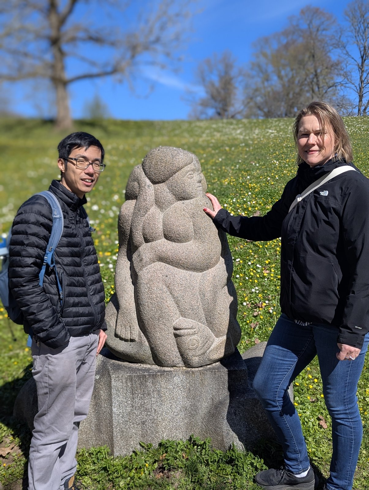 Daiga y un huésped junto a la escultura sentada de madre e hija en la Colina de las Dainas, Turaida