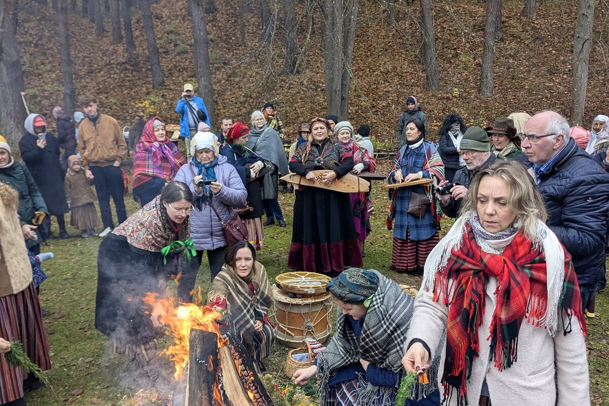 Visitantes con traje folclórico en torno a una hoguera de Mārtiņdiena en el Museo Etnográfico al Aire Libre de Letonia, Riga.