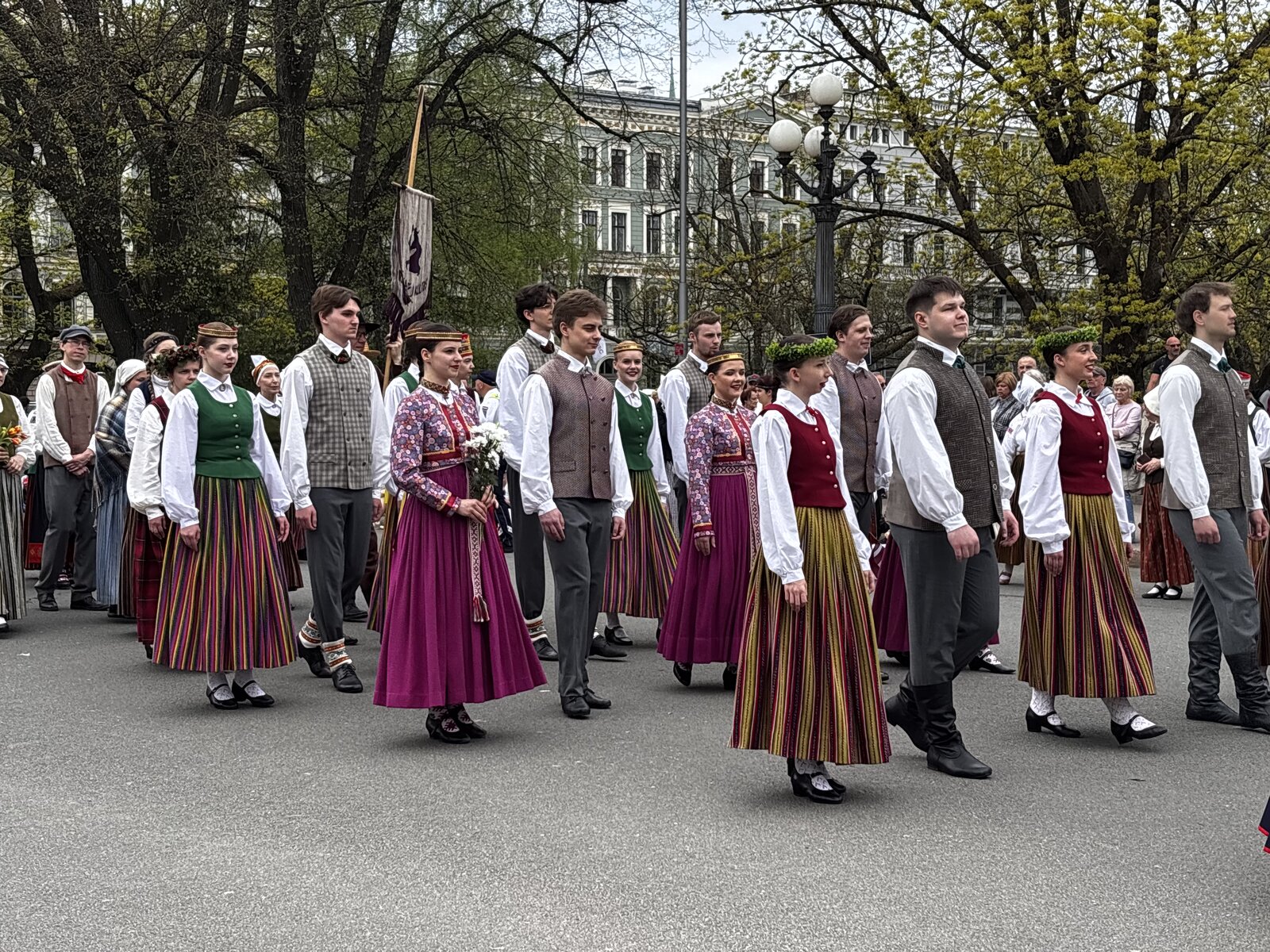 Procesión en traje folclórico junto al Monumento a la Libertad con la bandera letona en alto, Riga, 4 de mayo