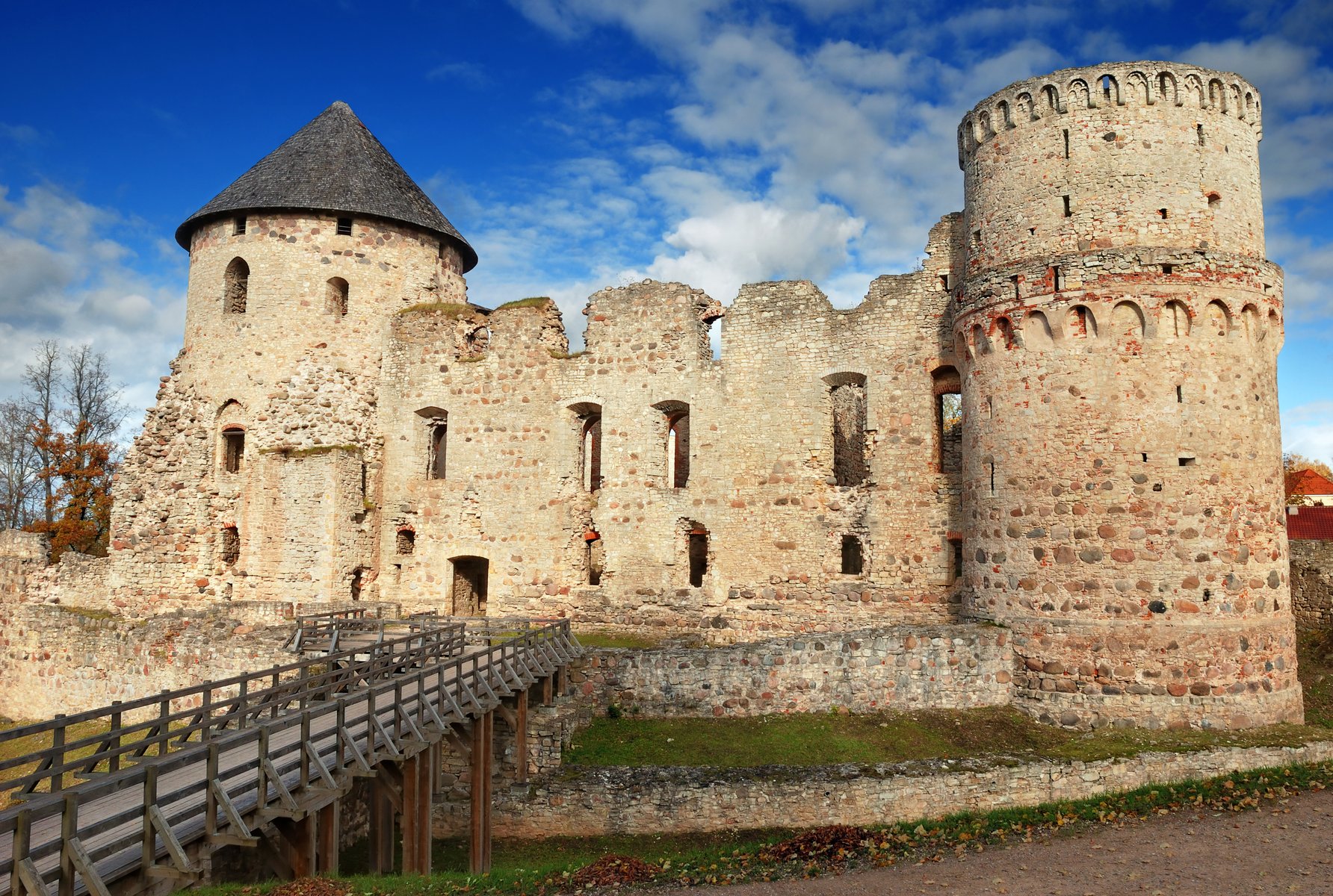 Exterior del castillo medieval de Cēsis, muros de ladrillo rojo bajo luz de otoño, Letonia
