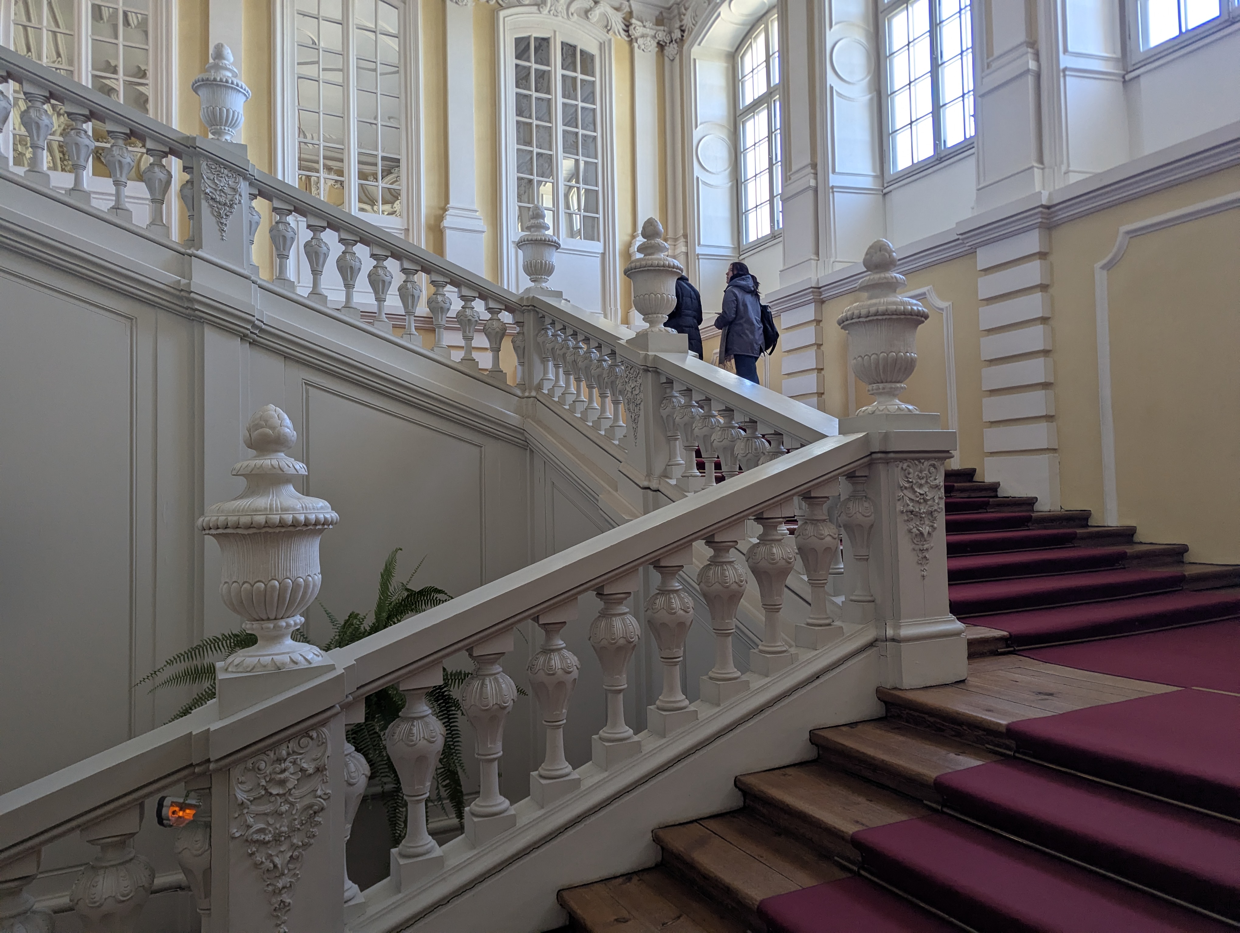 Escalera de honor del palacio de Rundāle con balaustradas de estuco blanco y alfombra granate