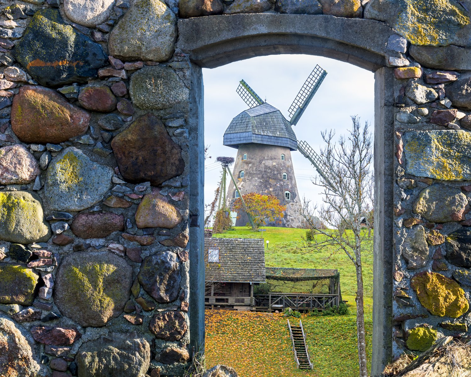 Un molino tradicional visto a través de un arco de piedra en una granja de Vidzeme