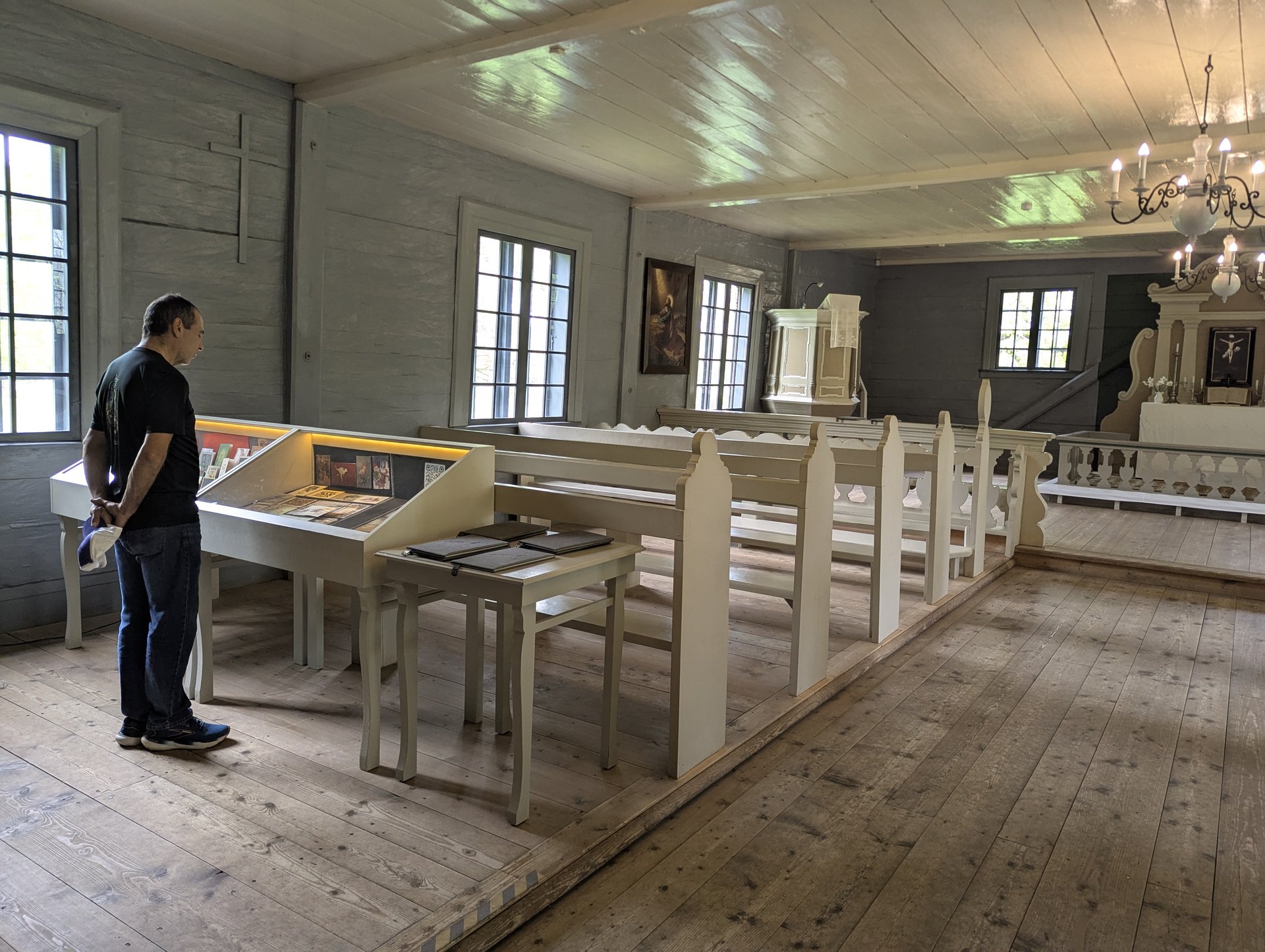 Interior del museo-iglesia de madera de Vidzeme con un visitante ante las vitrinas