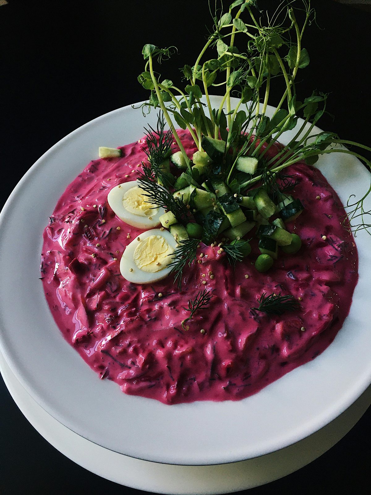 Un cuenco de aukstā zupa rosa intenso, la sopa fría letona de verano de kéfir y remolacha, decorada con huevo cocido, pepino y eneldo