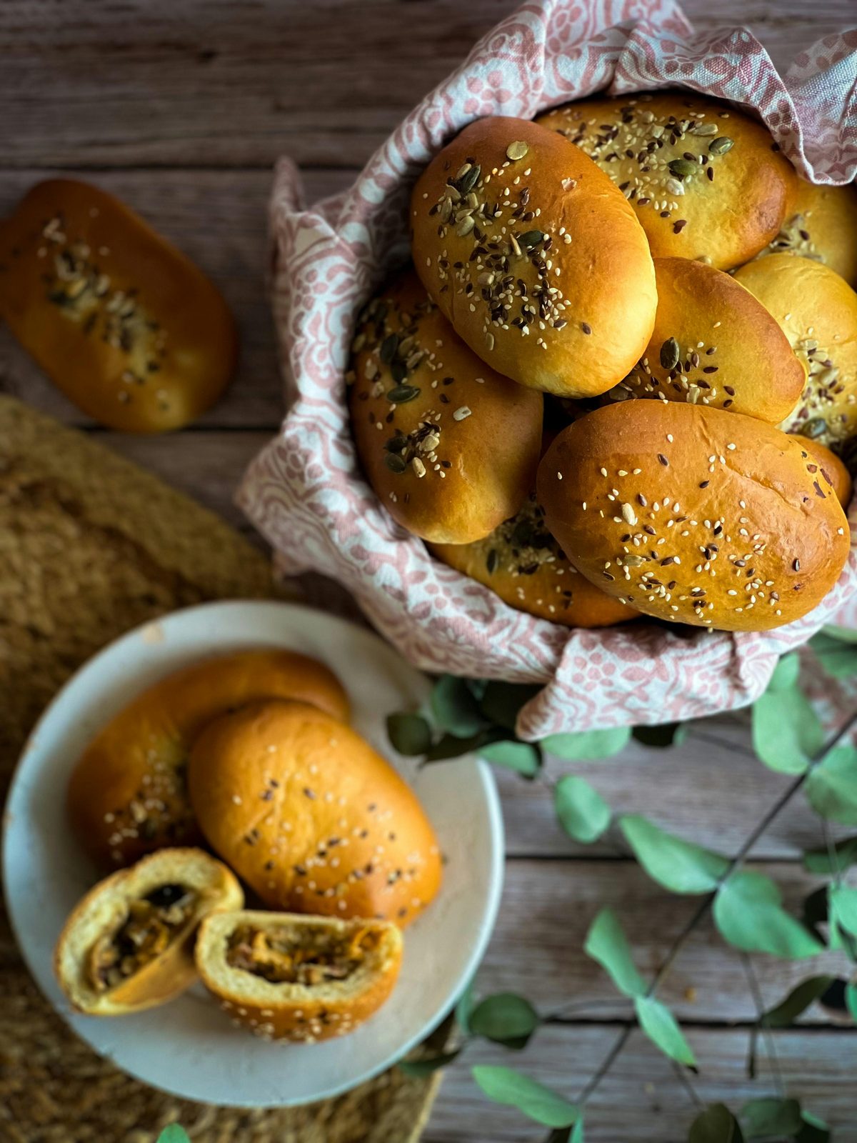 Una cesta de pīrāgi letones dorados espolvoreados con semillas, los pequeños bollos rellenos tradicionales
