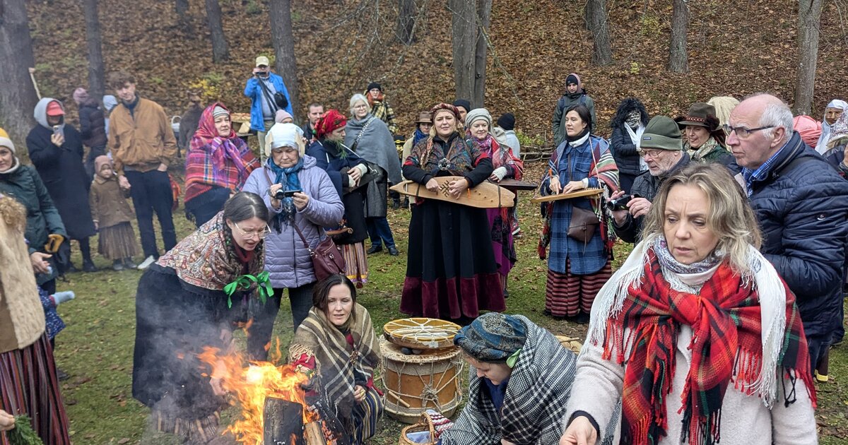 Visitantes con traje folclórico alrededor de una hoguera de Mārtiņdiena en el Museo Etnográfico al Aire Libre de Letonia, Riga.